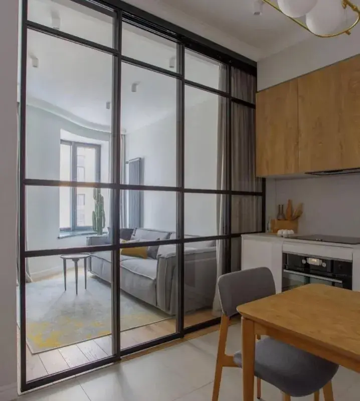 Интерьер небольшой кухни-гостиной со стеклянной перегородкой