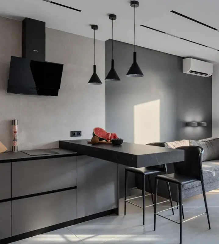 серый диван в интерьере кухни-гостиной с черными светильниками